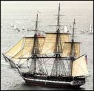 A photograph of Constitution sailing in Massachusetts Bay with six sails set and a crowd of civilian boats with passengers aboard observing